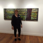 Woman artist standing in front of her painting.