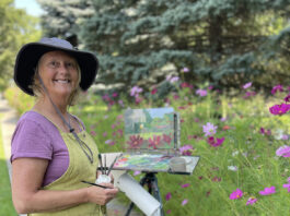 artist posing with her painting out in field
